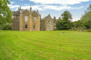 A large stone building with multiple windows and a well-maintained lawn in front.