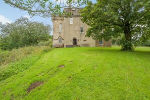 A historic stone building with a large lawn in front.