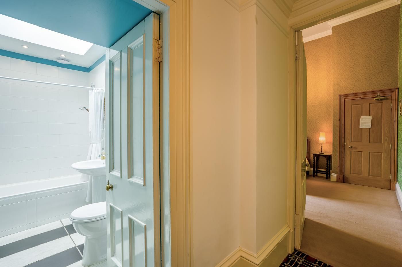 Une salle de bain équipée d’une baignoire, de toilettes et d’une porte donnant sur un couloir.