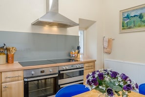 A kitchen with a stove, oven, and a dining table with chairs.