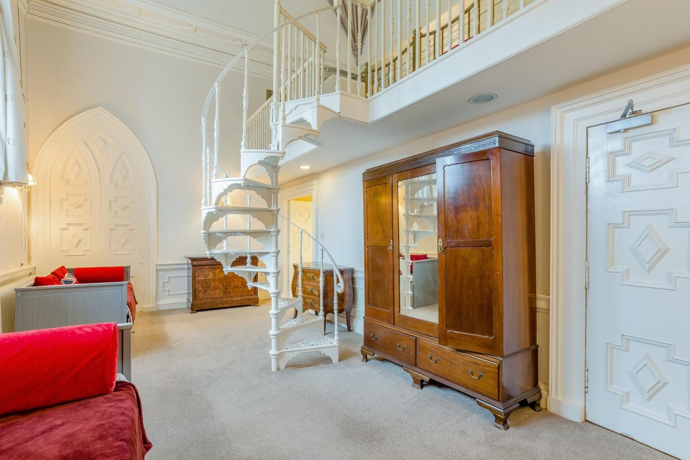 Une pièce spacieuse avec un magnifique escalier, une grande armoire en bois et un coin salon confortable.