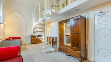 Une pièce spacieuse avec un magnifique escalier, une grande armoire en bois et un coin salon confortable.