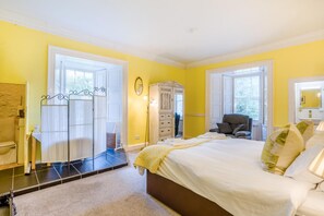 A bedroom with a bed, a chair, a wardrobe, and a mirror.