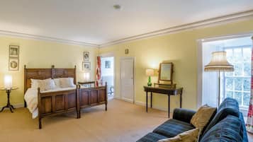 A room with a bed, a sofa, a table with a lamp, and a mirror.