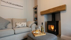 En stue med en sofa, pejs, bogreol og en bakke med en flaske og glas.