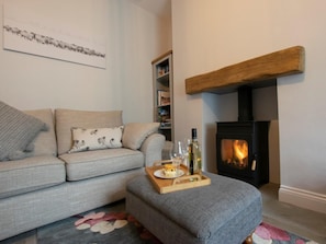 Ein Wohnzimmer mit einer Couch, einem Kamin, einem Bücherregal und einem Tablett mit Flasche und Gläsern.