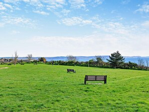 A grassy field with benches and a clear view of the sea in the distance. - 2 Bed in Weymouth (oc-95037) (Weymouth)