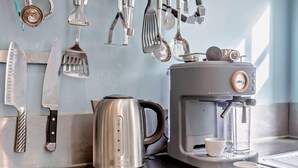 Una cocina con cafetera, hervidor y utensilios en la pared.