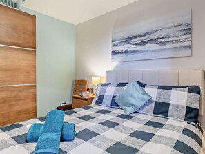 A hotel room with a checkered bedspread, a view of the sea, and a wooden wardrobe. - 2 Bed in Weymouth (oc-95037) (Weymouth)
