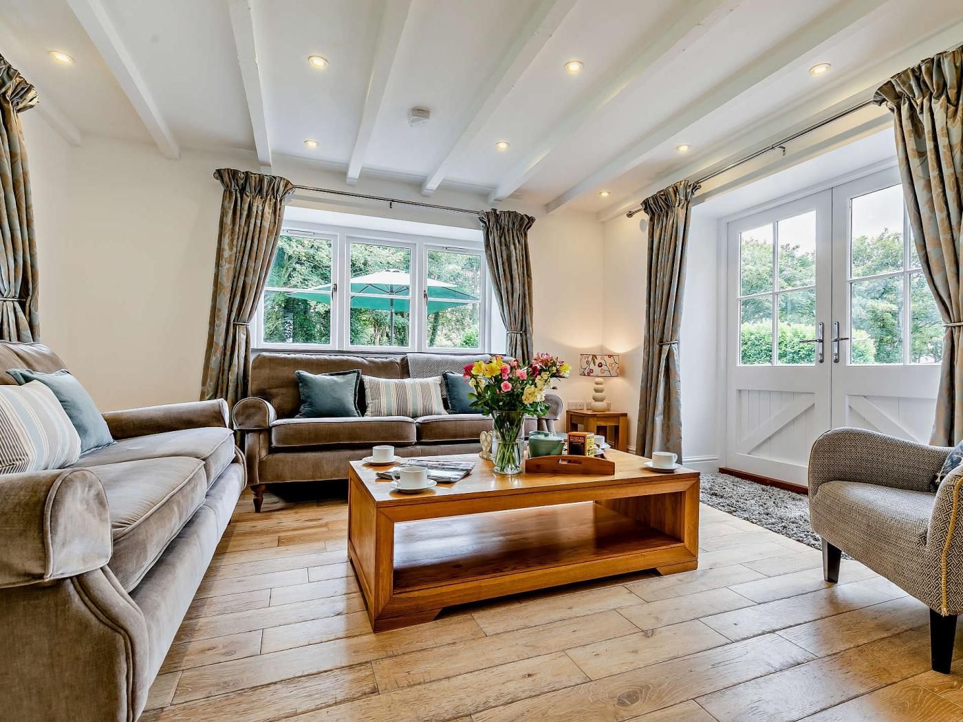 A living room with a sofa, a wooden coffee table, and a window with curtains.