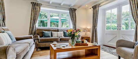 A living room with a sofa, a wooden coffee table, and a window with curtains.