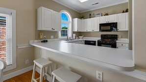 A kitchen with white cabinets, a large island, a microwave, and a stove. - Unwind At The Riverwalk, Spacious 2BR Retreat (Myrtle Beach)
