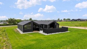 A modern black house with a large patio, surrounded by a grassy field and a clear sky. - VillaVilla 955 - Skåstrup Strand, Fyn og øer (Bogense)