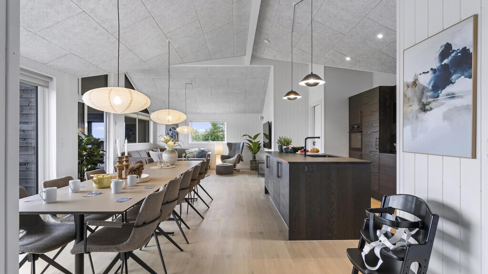 Une cuisine moderne dotée d’un îlot central, de luminaires suspendus et d’une grande fenêtre.