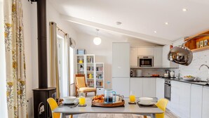 Une cuisine moderne avec des meubles blancs, une cuisinière noire et un coin repas avec une table dressée pour deux personnes.