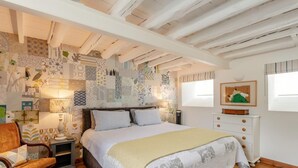 Een slaapkamer met een bed, nachtkastjes, een stoel, een kaptafel en een wand met behang.