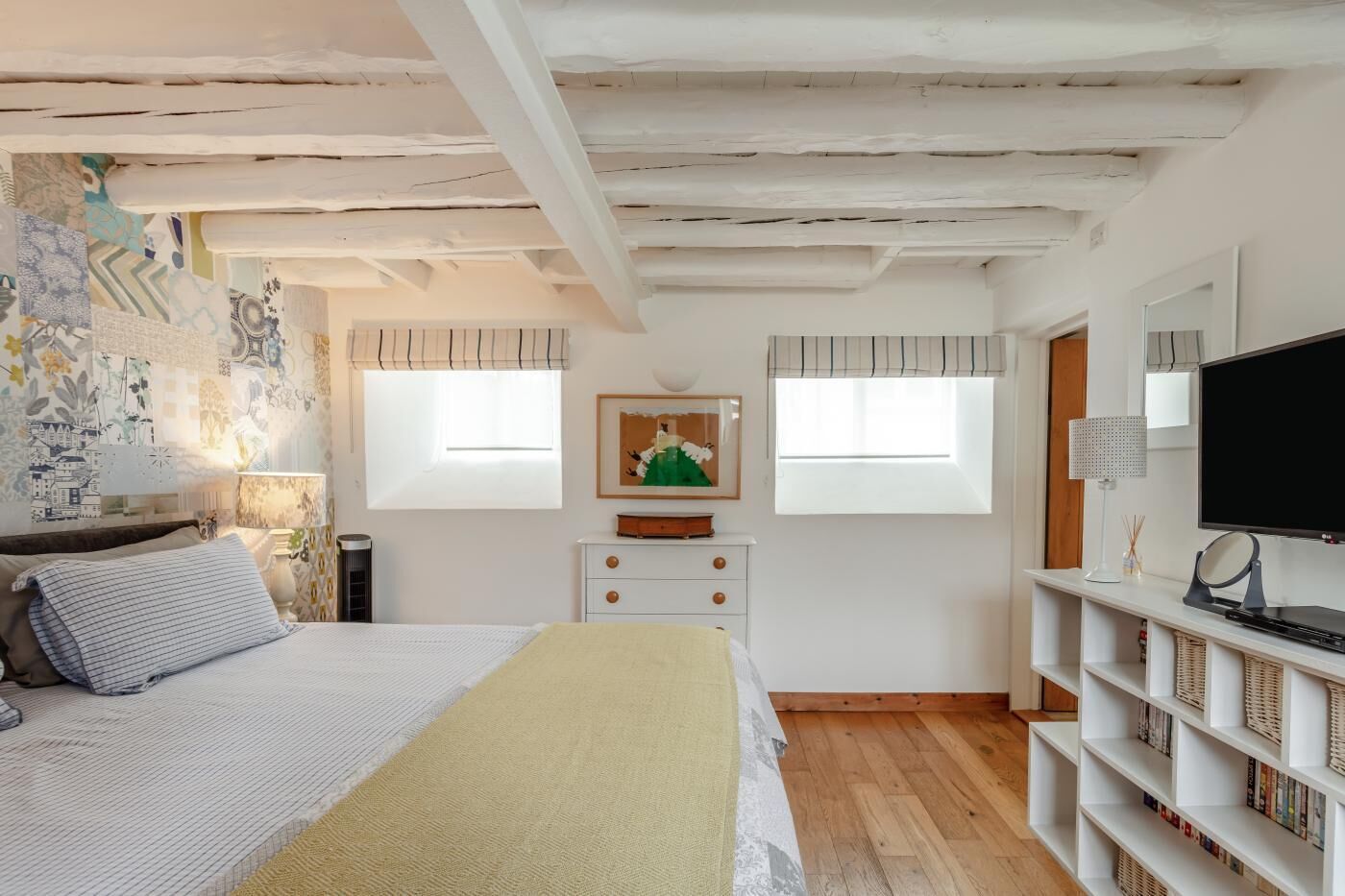 Une chambre à coucher avec un lit, une table de chevet, une lampe, un téléviseur et une bibliothèque.