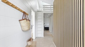 A hallway with a wooden bench, a hanging woven bag, and a bed visible in the distance. - VillaVilla 967 - Bønnerup Strand, Østjylland (Glesborg)