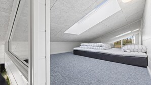 Ein Schlafzimmer mit Dachfenster, einem Bett mit Kissen und Blick ins Freie.