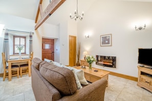 Una sala de estar con sofá, televisión, chimenea y un comedor con mesa y sillas.