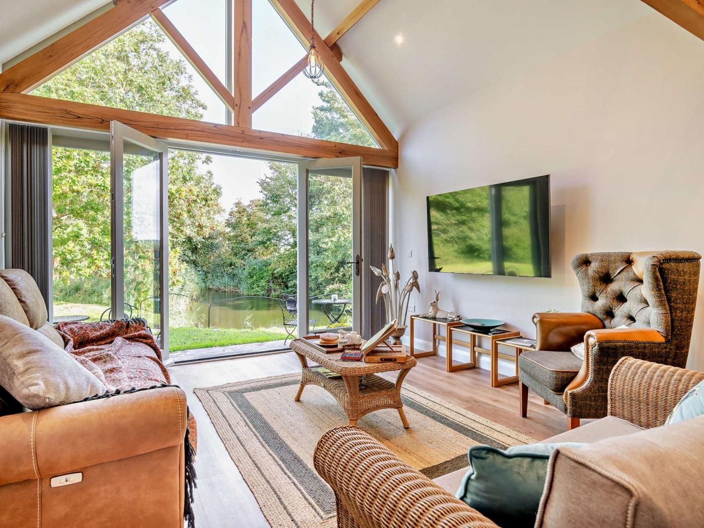 A spacious living room with a high ceiling, large windows, and a view of a garden.