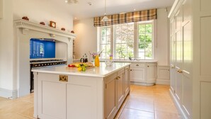 Una cocina con una isla central, un electrodoméstico azul y una ventana que ofrece vistas a zonas verdes.