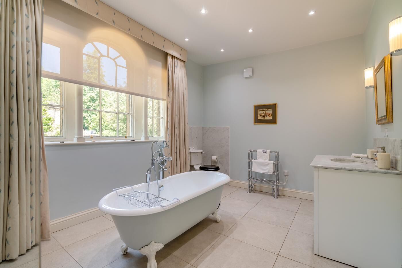 Une salle de bain avec une baignoire sur pieds, un meuble-lavabo et un porte-serviettes.
