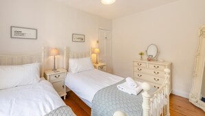 Un dormitorio con dos camas, mesitas de noche, un aparador y un espejo.