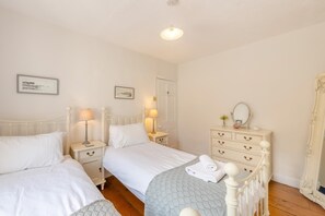Ein Schlafzimmer mit zwei Betten, Nachttischen, einem Schminktisch und einem Spiegel.