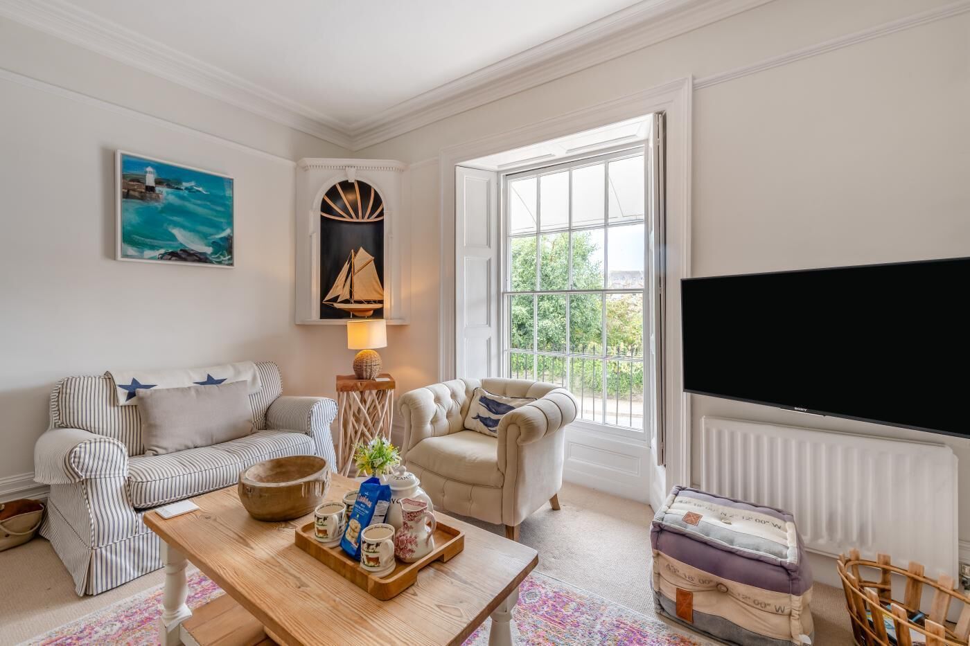 A living room with a sofa, armchairs, a coffee table with a tray, a lamp, and a television.