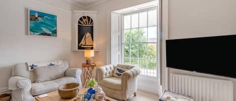 A living room with a sofa, armchairs, a coffee table with a tray, a lamp, and a television.
