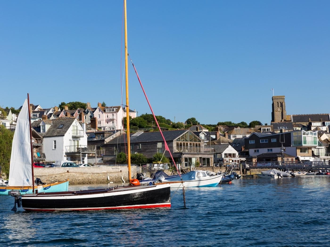 A harbor with boats, a prominent church tower, and residential buildings.