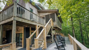 A wooden deck with outdoor seating, a staircase, and a building with multiple levels. - Private Cabin · Creekside · Hot tub · Fire pit · Only 1hr to Nashville (Nunnelly)