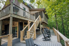 Eine Holzterrasse mit Sitzgelegenheiten im Freien, einer Treppe und einem mehrstöckigen Gebäude.