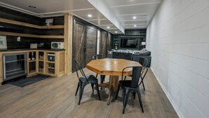 A compact kitchen with a dining table and chairs, wooden cabinets, and a microwave. - Private Cabin · Creekside · Hot tub · Fire pit · Only 1hr to Nashville (Nunnelly)