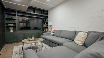 A modern living room with a sectional sofa, a small round coffee table, and a built-in bookshelf.