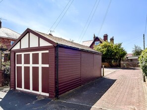 A red garage with a white door, adjacent to a brick house with a pitched roof. - 2 Bed in Filey (oc-49508) (Filey)