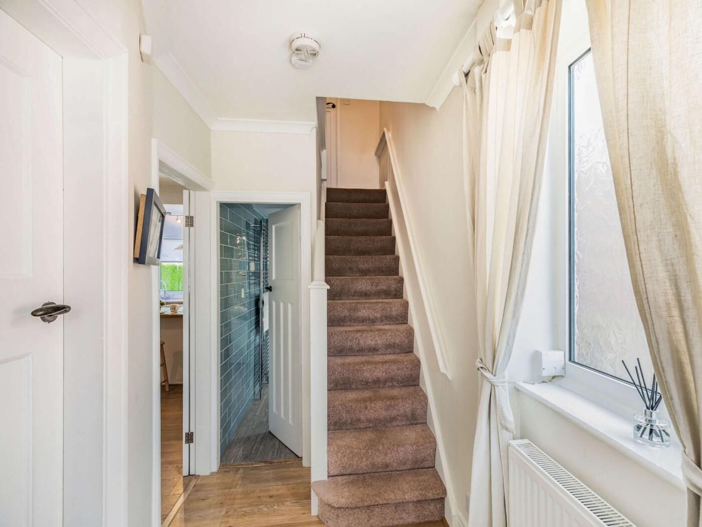 A staircase with carpeted steps leading to a room with a window and a radiator.