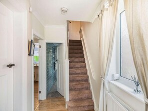 A staircase with carpeted steps leading to a room with a window and a radiator. - 2 Bed in Filey (oc-49508) (Filey)