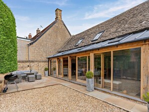 A building with a stone facade, large windows, and a gravel patio with outdoor furniture.