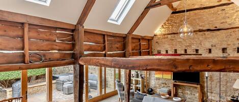 A spacious interior with high ceilings, wooden beams, and large windows.