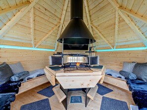 A cozy cabin interior with a central wood-burning stove, wooden walls, and a sloped ceiling. - 3 Bed in Carlisle (oc-94673) (Arthuret)