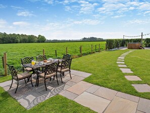 A patio with a table and chairs, a wooden deck, and a stone pathway leading to a wooden structure. - 3 Bed in Carlisle (oc-94673) (Arthuret)