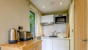 A compact kitchen with a toaster, kettle, and sink.