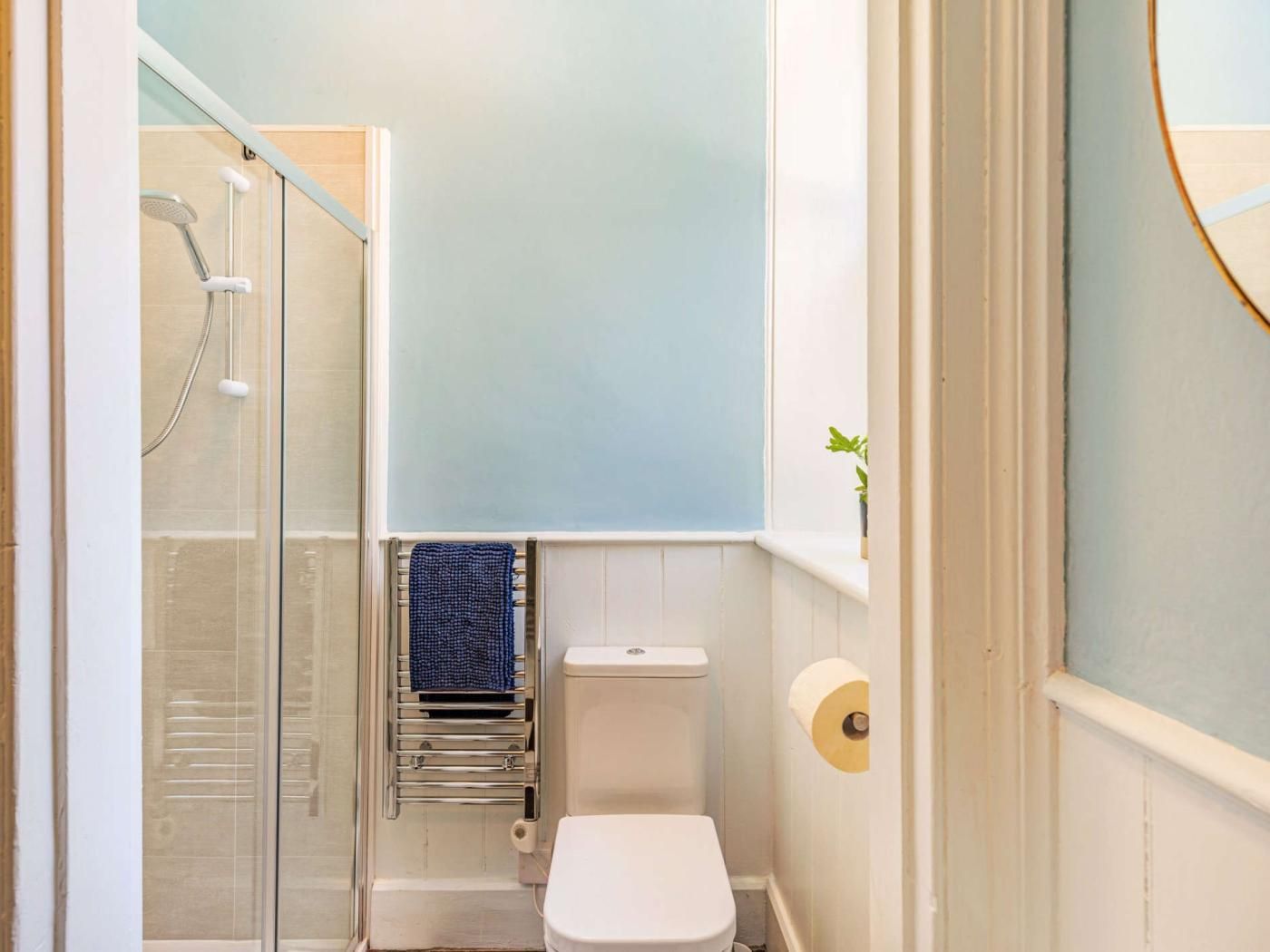 Ein Badezimmer mit Duschkabine aus Glas, einer weißen Toilette und einem Handtuchhalter.