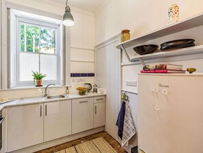 Eine Küche mit Fenster, Spüle, Herd und Kühlschrank.