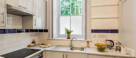 Una cocina con ventana, un lavamanos, armarios, una estufa y una encimera.