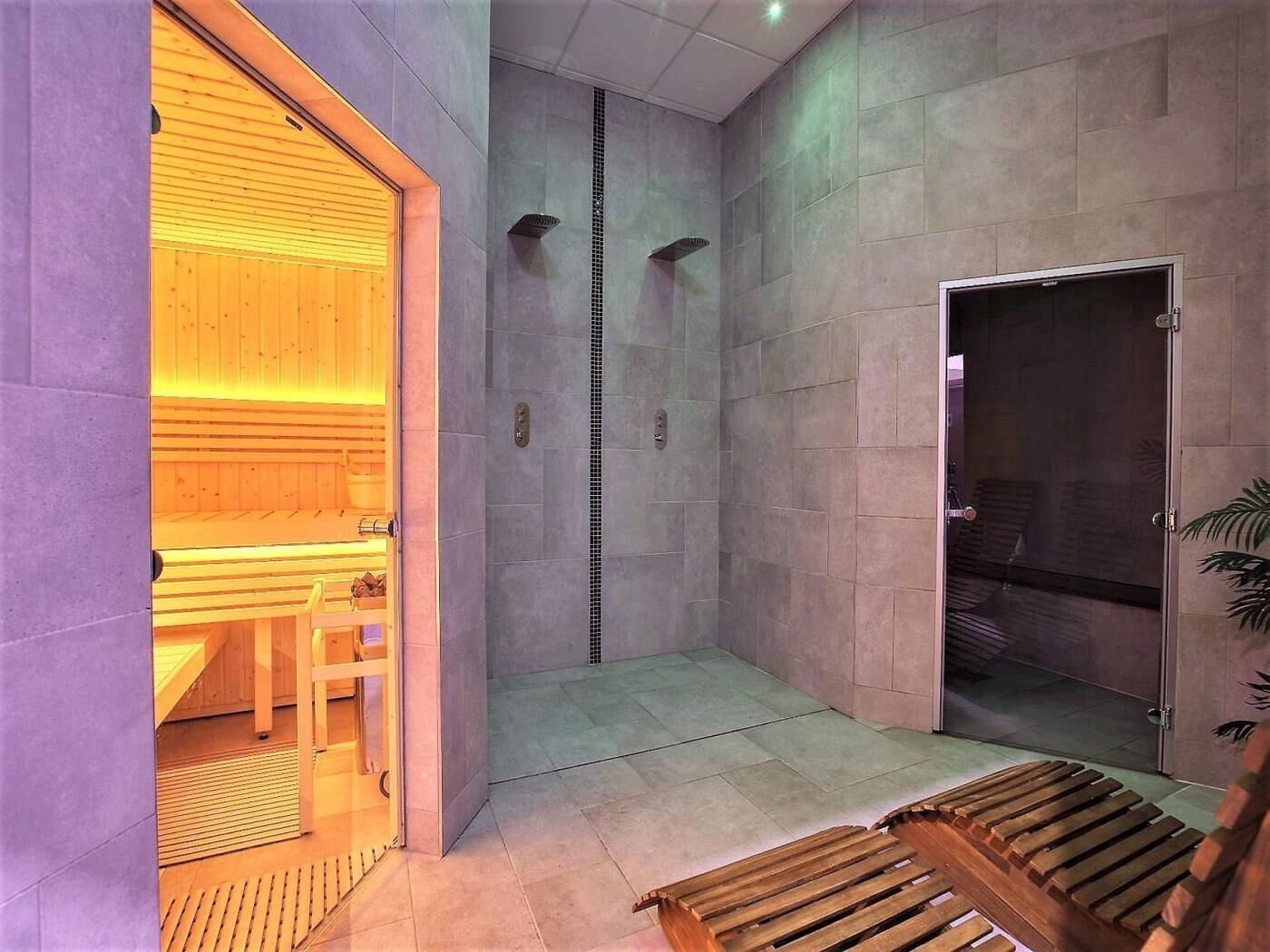 A modern spa room with a wooden sauna, a shower area, and a bench.