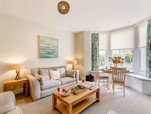 Ein Wohnzimmer mit einer Couch, einem Couchtisch und einem Essbereich mit Stühlen.