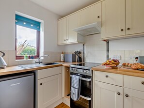 A compact kitchen with a dishwasher, stove, oven, and a window with a view of greenery. - 1 Bed in Wells (oc-94958) (Wookey)